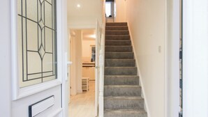 A staircase leading to a kitchen area with white walls and a light wooden floor. - Beau Jardin (Telford)