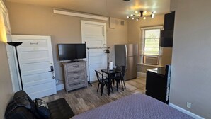 A compact room with a bed, a TV, a small dining table, a refrigerator, and a ceiling fan. - Iron Rider Studio - Couples Motorcycle Theme Loft Walkable Downtown Hot Springs (Hot Springs)