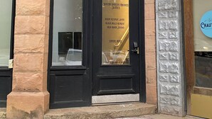 A building corner with a black-framed door, stone pillars, and a sign for 'South Dakota Rhodes Suites' with amenities listed. - Iron Rider Studio - Couples Motorcycle Theme Loft Walkable Downtown Hot Springs (Hot Springs)