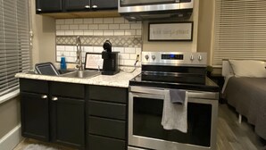 A compact kitchen with dark cabinets, a microwave, a stove, and a sink. - Iron Rider Studio - Couples Motorcycle Theme Loft Walkable Downtown Hot Springs (Hot Springs)