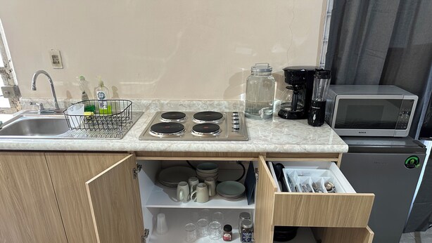 A compact kitchen with a built-in stove, a microwave, and a coffee maker. - Apt. with double bed and patio 20 min. from the historical center (Heroica Puebla de Zaragoza)