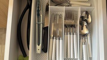 A drawer with compartments containing various kitchen utensils.