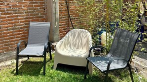 A brick wall, two chairs, and a bamboo plant in a garden. - Apt. with double bed and patio 20 min. from the historical center (Heroica Puebla de Zaragoza)