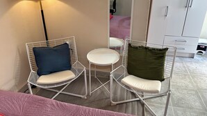 A room with two white wire-framed chairs, a small white table, a floor lamp, a mirror, and a wardrobe. - Apt. with double bed and patio 20 min. from the historical center (Heroica Puebla de Zaragoza)