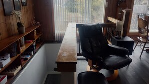 Una habitación con un escritorio de madera, una silla de oficina negra, una estantería y una ventana con persianas.