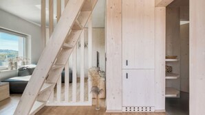 A wooden staircase leading to a loft bedroom with a view of the outdoors.