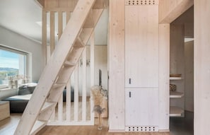 A wooden staircase leading to a loft bedroom with a view of the outdoors.