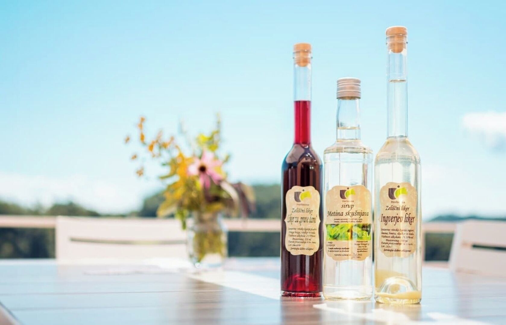Tres botellas de bebidas sobre una mesa, con un cielo despejado al fondo.