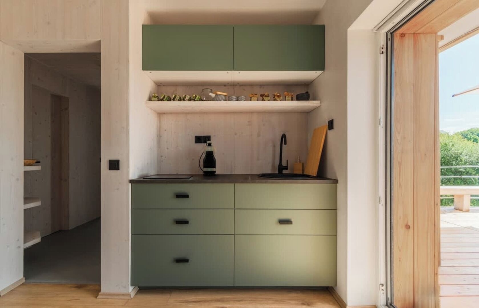 A compact kitchen with a green cabinet, a sink, and a window.