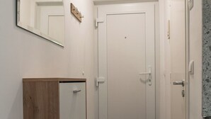 A narrow hallway with a wooden wardrobe, a white door, and a mirror on the wall.