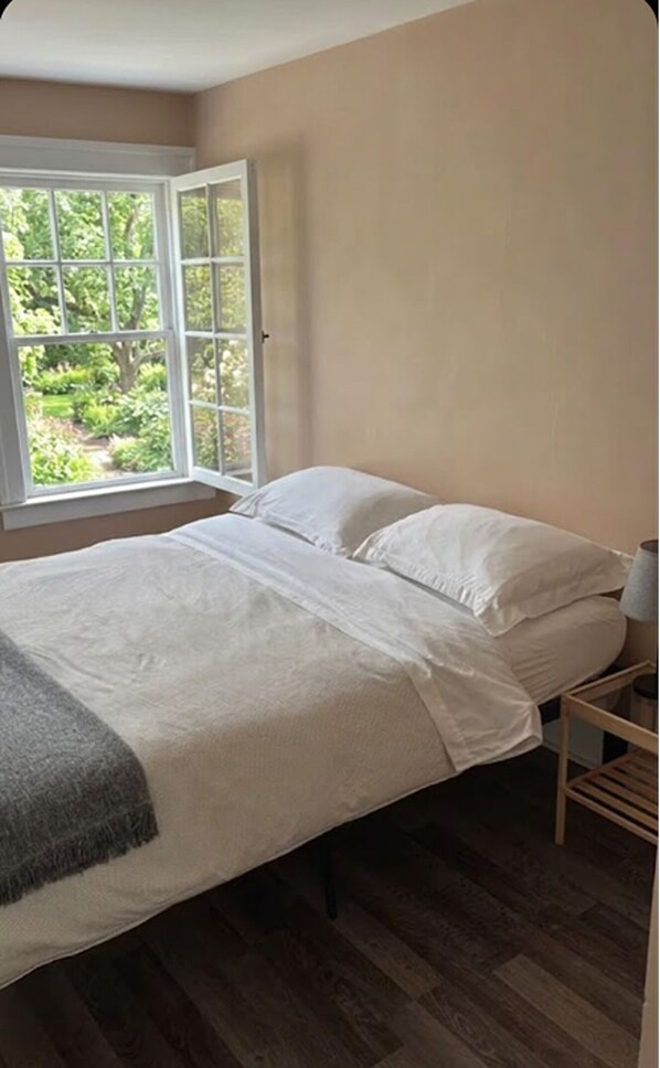 A bedroom with a bed, a window, and a view of greenery outside. - Modern 1BR Apartment | Parking & WiFi (Windsor)