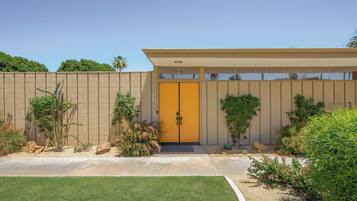 A modern building with a yellow door, beige exterior, and a covered entrance area.
