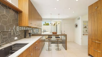 A modern kitchen with wooden cabinets, a stainless steel sink, and a bar area with stools.