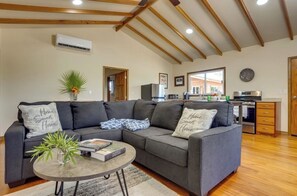 Ein modernes Wohnzimmer mit einem Ecksofa, einem Couchtisch und einer Küchenzeile im Hintergrund.