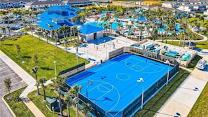 An aerial view of a resort with a large blue pool, multiple tennis courts, and a well-maintained landscape with palm trees. - Windsor Island | 5 Br 14ppl | Pool, WATER PARK (Davenport)