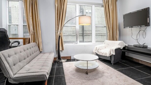 Een moderne woonkamer met een bank, een ronde salontafel, een televisie en een lamp.