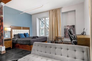Een slaapkamer met een bed, een bureau, een stoel en een bank.