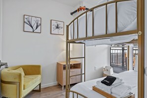 A bunk bed room with a yellow armchair, a wooden cabinet, and two framed pictures on the wall. - Elegant 2BR | St Charles Entertainment Area (Saint Charles)