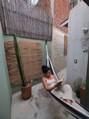 A person sitting on a hammock in a courtyard with a cactus and a wall with a drawing. - Our guests appreciate the prime location, comfort, service, and Wi-Fi (Oaxaca de Juárez)