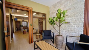 A modern interior with a wooden bench, two black chairs, a potted plant, and a stone wall. - Arenal Volcanic Villas (La Fortuna)