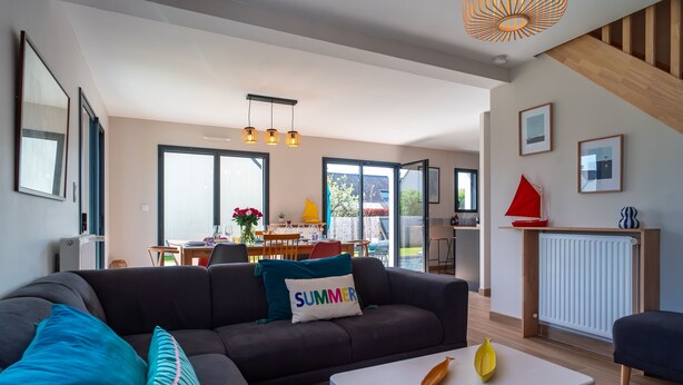 Una sala de estar moderna con un sofá, una mesa de centro y un comedor al fondo.
