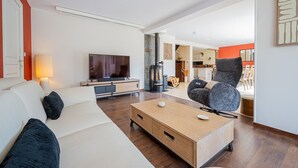 En moderne stue med sofa, fjernsyn, sofabord i træ og en pejs.