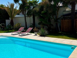 Ein Pool mit Liegestühlen, umgeben von Palmen und einem Holzzaun.