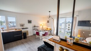 Moderni keittiö, jossa on ruokailutila, suuret ikkunat ja näkymä ympäröiviin rakennuksiin.