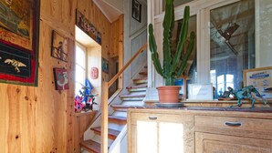 Un escalier en bois orné d’un cactus sur la plateforme, un meuble en bois avec des tiroirs et une fenêtre offrant une vue agréable.