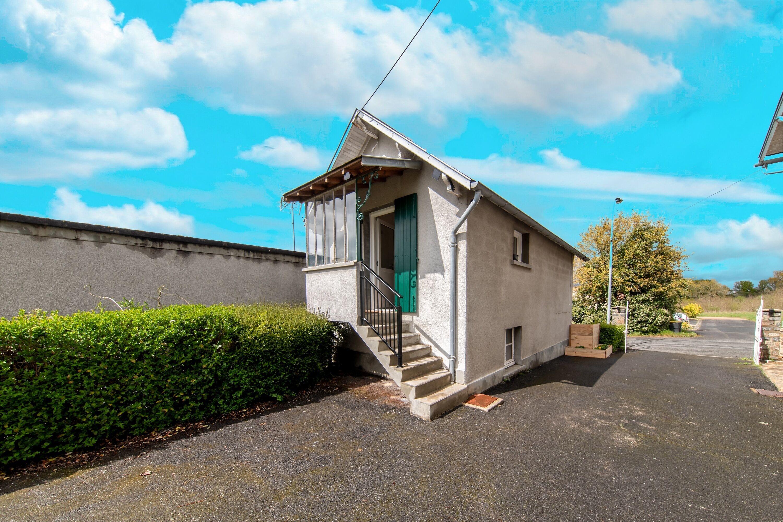 A small, single-story building with a green door and a staircase leading to the entrance.