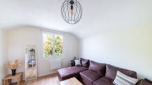 Ett modernt vardagsrum med en brun lädersoffa, ett träbord, en spegel och en hängande lampa.