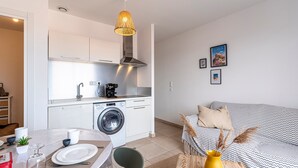 Une cuisine moderne équipée d’un lave-linge, d’une table à manger et d’un canapé dans l’espace salon.
