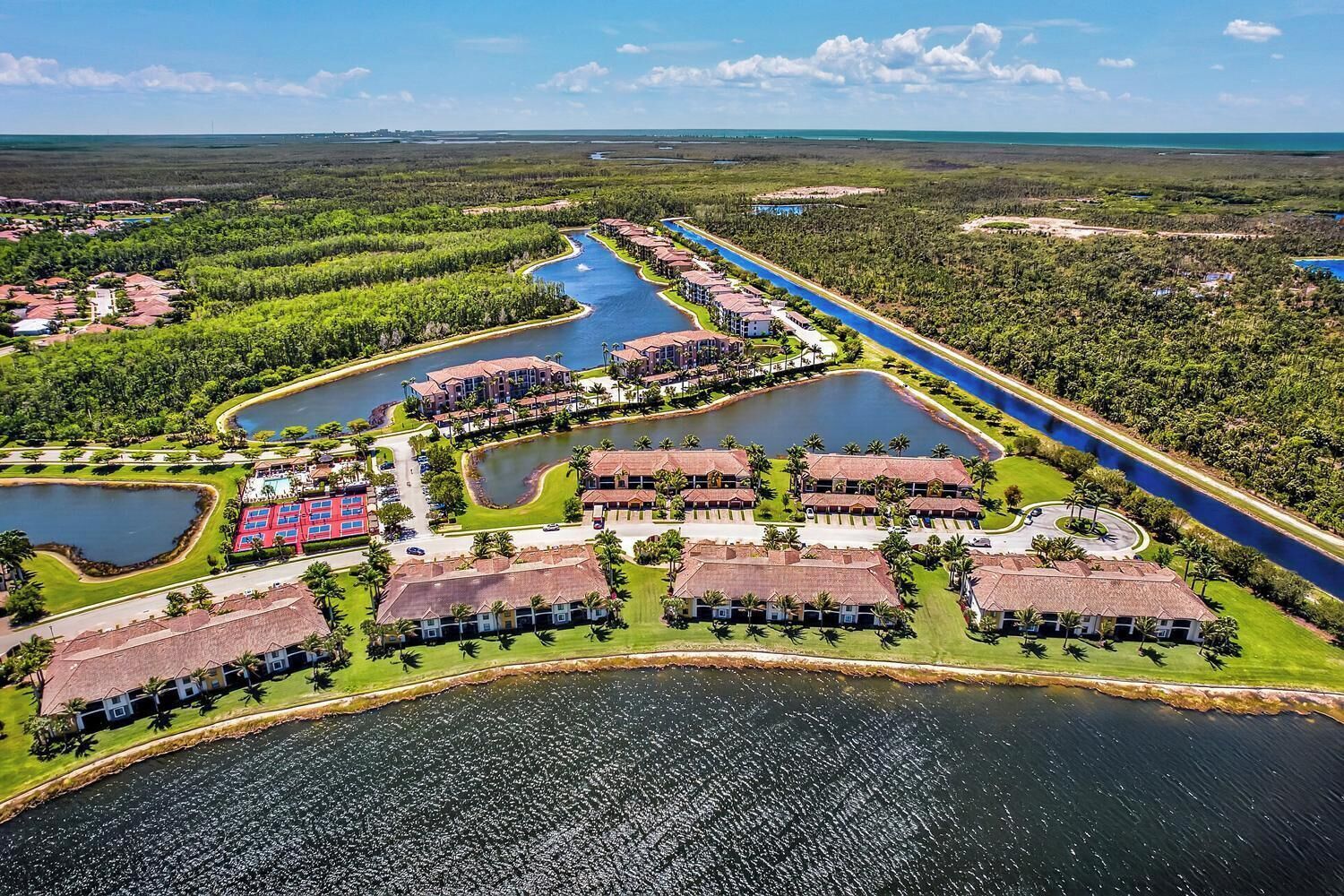 Eine Luftaufnahme eines Resorts mit mehreren Gebäuden, einem zentralen Kanal und umliegender Bepflanzung.