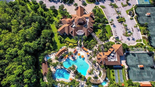 Eine Luftaufnahme eines Resorts mit einem zentralen Schwimmbecken, einem Tennisplatz und einem Gebäude mit einer Kuppel.