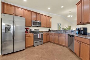 A kitchen with wooden cabinets, stainless steel appliances, granite countertops, and a built-in microwave. - Treviso Bay Retreat I Resort-Style Amenities I Relaxing Lakeview Escape (Naples)