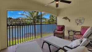 Ein Balkon mit Blick auf ein Gewässer, einem Deckenventilator und Korbmöbeln.