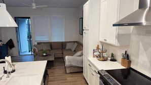 A modern kitchen with white cabinets, a black stove, and a dining area with a white table and chairs. - FIFA 2026 RETREAT - 2BR Sleeps 6 - Bikes - BeltLine to Stadium - Walkable (Atlanta)