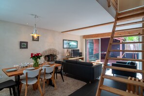 Ein modernes Wohnzimmer mit Essbereich, Kamin, Fernseher und einer Holztreppe.