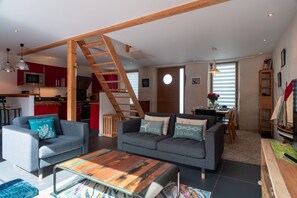 Ein modernes Wohnzimmer mit einem grauen Sofa, einem Holztisch und einer Treppe.