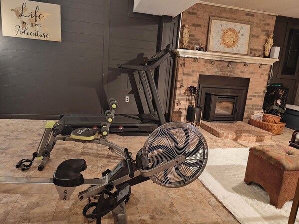 A home gym with exercise equipment, a fan, and a fireplace.