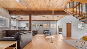 A spacious living area with a wooden ceiling, a sofa, a dining table, and a staircase. - Rêve St-Viateur (Joliette)