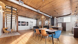 A spacious dining area with a long table, multiple chairs, and a hanging light fixture. - Rêve St-Viateur (Joliette)