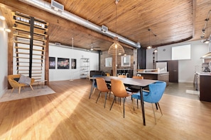 A spacious dining area with a long table, multiple chairs, and a hanging light fixture.