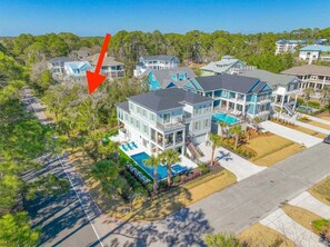 A multi-story residential building with a swimming pool, surrounded by trees and other houses. - New Construction, Quick Walk to Beach, Chefs Kitchen, Pool, Free Golf (Hilton Head Island)
