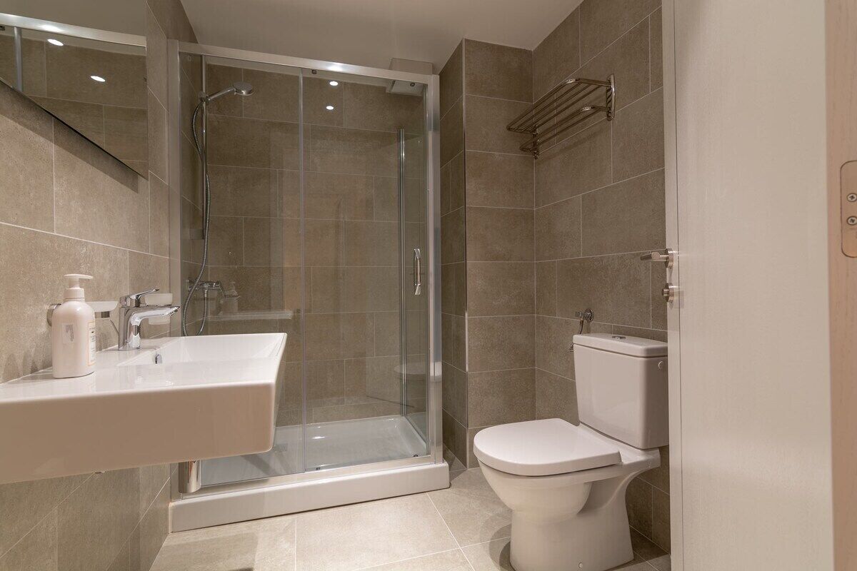 A modern bathroom with a glass-enclosed shower, a white sink, and a toilet.
