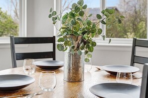 A dining table with a vase of green foliage, black chairs, and empty plates and glasses. - Hot Tub + Gym + Workstations | Family Favorite (Broomfield)