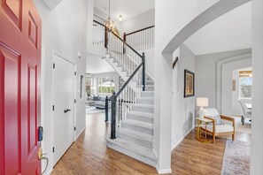 A staircase with a black handrail, white walls, and a red door. - Hot Tub + Gym + Workstations | Family Favorite (Broomfield)