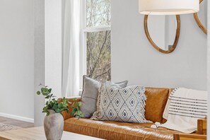 A cozy living room with a leather sofa, a patterned throw pillow, a vase with greenery, and a wall-mounted lamp. - Hot Tub + Gym + Workstations | Family Favorite (Broomfield)