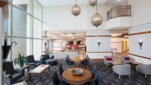 En rummelig lobby med et centralt siddeområde, en trappe og udsigt til køkkenområdet.