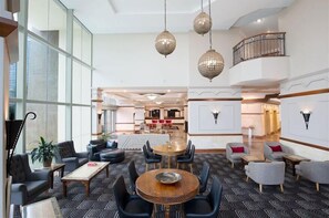 A spacious lobby with a central seating area, a staircase, and a view of the kitchen area. - Coastal Escape - Sun City (Gold Coast)